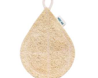 Op de afbeelding: Een lichtbruine loofah spons in de vorm van een traan met een wit katoenen lusje. De spons heeft een geweven textuur en de merknaam "MOC XO" is gedrukt op een wit label dat aan de lus is bevestigd.