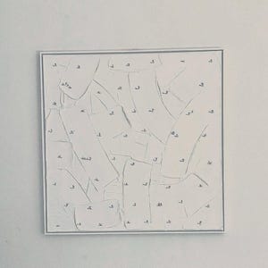 May include: Abstract white artwork in a silver frame. The textured surface features overlapping shapes with small, dark markings. The piece has a minimalist aesthetic, suitable for modern decor.