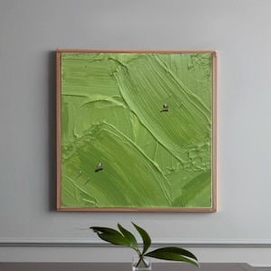 Può includere: Dipinto astratto incorniciato, con una superficie strutturata verde brillante. L'opera presenta pennellate visibili e piccole figure metalliche. La cornice è marrone chiaro. Stile moderno.