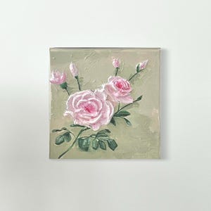 Könnte beinhalten: Quadratische Leinwandkunst mit einem Blumenstillleben. Das Gemälde zeigt rosa Rosen mit grünen Blättern und Stielen vor einem strukturierten, hellgrünen Hintergrund. Das Kunstwerk ist eine Nahaufnahme der Blumen.
