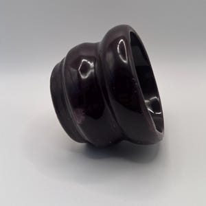 Könnte beinhalten: Ein kleiner, dunkelvioletter Keramiktopf mit einem welligen, strukturierten Design.