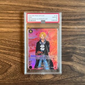 May include: A graded One Piece trading card featuring the character Sabo in a red manga alternate art style. The card is encased in a clear protective plastic slab with a label at the top reading 2025 ONE PIECE OP13 EN SABO RED MANGA ALTERNATE ART.