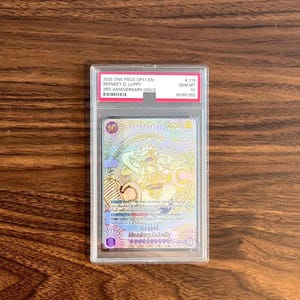 Puede incluir: Una carta coleccionable 2025 One Piece OP11 EN Monkey D. Luffy 3rd Anniversary Gold graduada en una funda de plástico transparente. La carta presenta una ilustración colorida y detallada del personaje con detalles dorados, calificada como GEM MT 10.