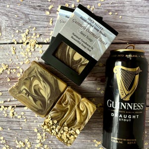 Peut inclure: Savons artisanaux au stout d'avoine Guinness avec un motif marbr&eacute;, et une canette de Guinness draught stout. Le savon est pr&eacute;sent&eacute; dans des bo&icirc;tes noires avec du texte blanc. La canette est noire avec des lettres dor&eacute;es et un logo de harpe.