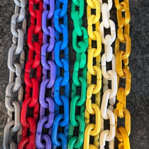 May include: A collection of colorful plastic chain links in a rainbow of colors, including gray, red, purple, blue, green, yellow, white, and gold. The chains are arranged vertically, showcasing the variety of hues.