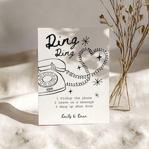 May include: A cream-colored card with a black line drawing of a vintage telephone, a heart-shaped cord, and the words "Ding Ring." Text below reads "1 Pickup the phone, 2 Leave us a message, 3 Hang up when done." The names "Emily & Evan" are at the bottom.