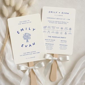May include: Two wedding fan programs with navy blue text on a cream background. One fan reads "Welcome to the Wedding of Emily + Evan" with a floral design. The other fan has the ceremony details and wedding party names. Each fan has a wooden handle and a white ribbon.