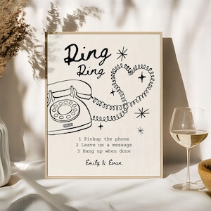 May include: A framed print with the words "Ring Ring" above a vintage telephone illustration. The phone cord forms a heart shape. Text below reads "1. Pickup the phone, 2. Leave us a message, 3. Hang up when done." Signed "Emily & Evan."