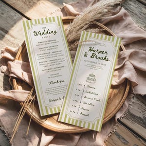 Könnte beinhalten: Zwei Hochzeitskarten mit grün gestreiften Rändern und elegantem Text. Eine Karte listet die Hochzeitsgesellschaft auf, die andere beschreibt den Ablauf der Zeremonie. Die Karten liegen auf einem Holztablett.