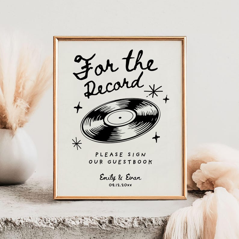 May include: A black and white sign with the text "For the Record" and a vinyl record graphic. The sign also includes the text "Please sign our guestbook" and the names "Emily & Evan" with the date "09.12.20xx".