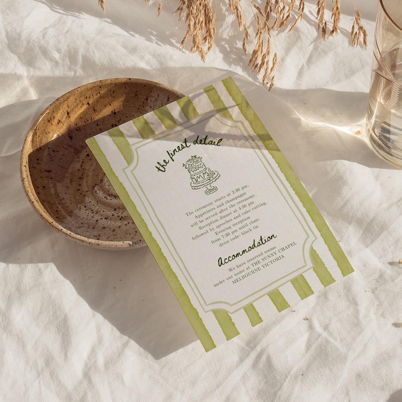 K&ouml;nnte beinhalten: Eine Hochzeitseinladung mit einem gr&uuml;n-wei&szlig; gestreiften Rand und dem Text "the finest detail". Die Einladung enth&auml;lt Details zur Zeremonie, zum Empfang und zum Dresscode. Eine Keramikschale und ein Glas befinden sich im Hintergrund.