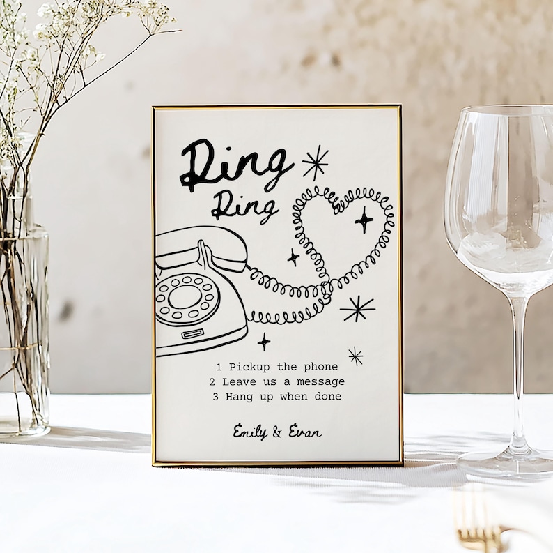 May include: A framed sign with a gold border features a black and white illustration of a vintage telephone and the words "Ring Ring". The text includes instructions and the names "Emily & Evan". The design incorporates a heart-shaped phone cord.