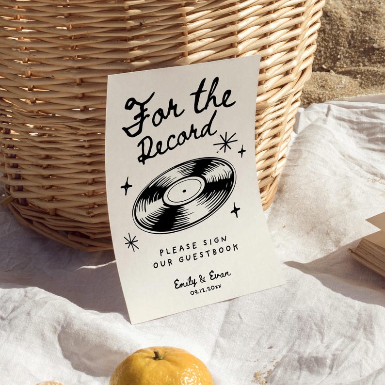 May include: A white sign with black text that reads "For the Record" with a black and white illustration of a vinyl record. The text below the record says "Please sign our guestbook" followed by "Emily & Evan" and the date "09.12.20xx".