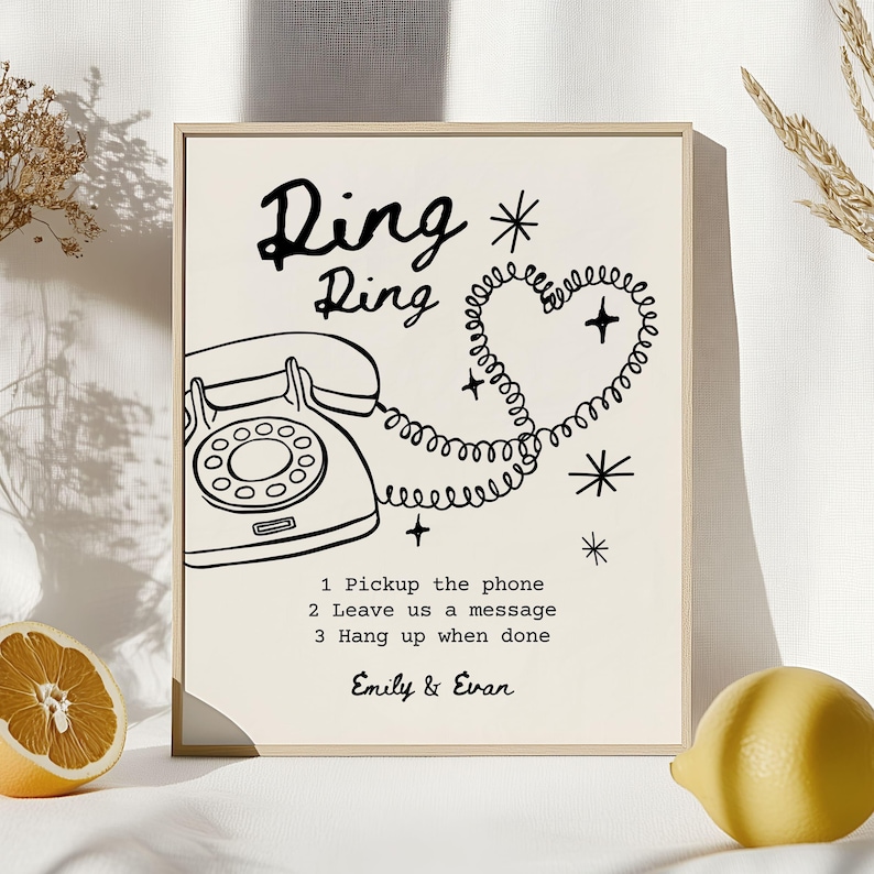 May include: A framed print with a cream background features a black illustration of a vintage rotary phone. The text "Ding Ring" is above the phone, with a heart-shaped phone cord. Instructions and names are below.