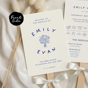 May include: Cream-colored wedding fan with navy blue text. The fan reads "Welcome to the Wedding of Emily & Evan" with the date and venue. A floral illustration is centered between the names. The fan is attached to a wooden stick with a white ribbon.