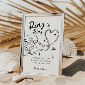 May include: A framed print with a silver border featuring a vintage telephone illustration. The text "Ring Ring" is above the phone, with instructions below: "1 Pickup the phone, 2 Leave us a message, 3 Hang up when done." The names "Emily & Evan" are at the bottom.