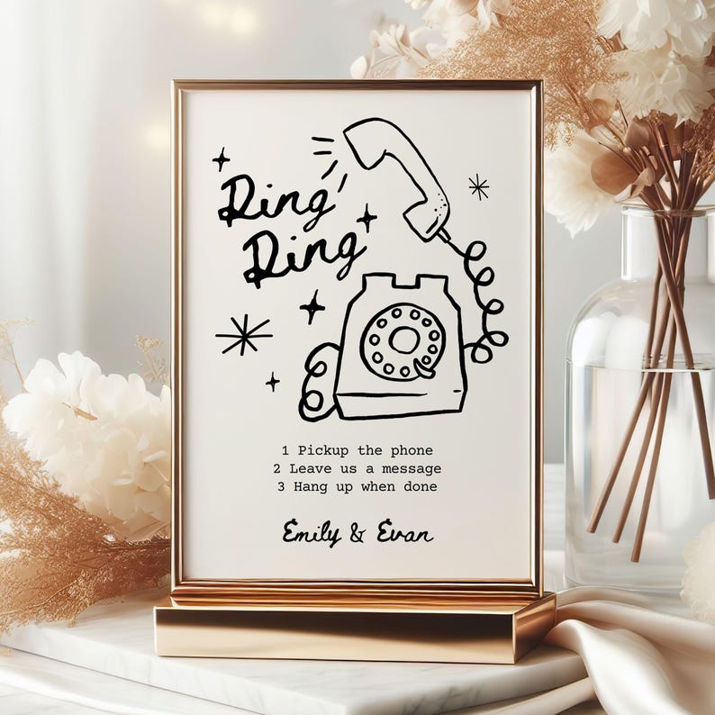 May include: A gold-framed sign with a black and white illustration of a rotary phone with the text "Ring Ring" and instructions to "Pickup the phone, Leave us a message, Hang up when done". The sign also includes the names "Emily & Evan".
