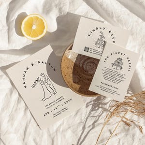 May include: Wedding invitation suite featuring minimalist line art of a couple and a tiered cake. The invitations are printed on cream-colored cardstock with black text. One card reads "Hannah & Dalton" and another says "Kindly RSVP". A halved lemon sits nearby.