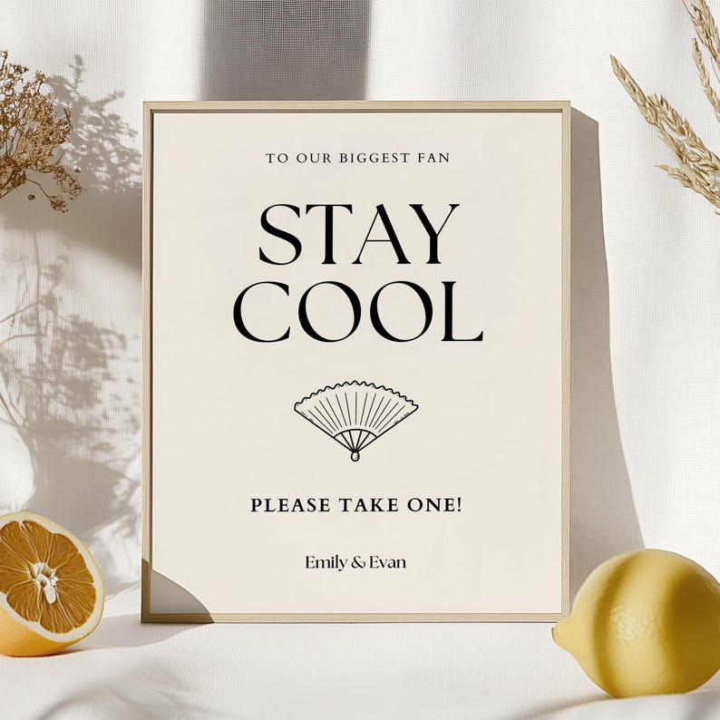 K&ouml;nnte beinhalten: Ein gerahmtes Schild mit dem Text "TO OUR BIGGEST FAN STAY COOL PLEASE TAKE ONE!" in Schwarz. Unter dem Text befindet sich eine Zeichnung eines F&auml;chers. Das Schild befindet sich auf einer wei&szlig;en Oberfl&auml;che mit einer Zitrone und einer Orangenscheibe.