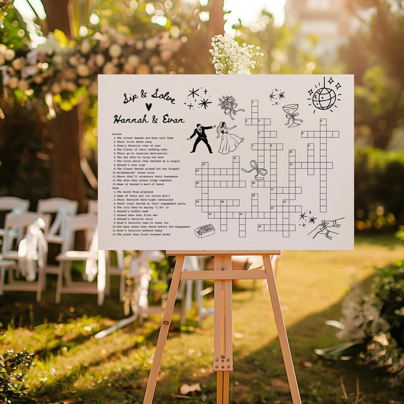 May include: A white sign on a wooden easel with a crossword puzzle design for a wedding. The sign includes the text "Sip & Solve" and the names "Hannah & Evan". The crossword puzzle has illustrations of a couple, a disco ball, and other wedding-related graphics.