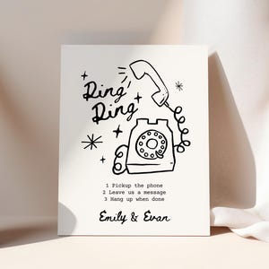 May include: Black and white illustration of a rotary phone with the text "Ring Ring" above it. The illustration includes stars and a plus sign. Below the phone is the text "1 Pickup the phone 2 Leave us a message 3 Hang up when done Emily & Evan".