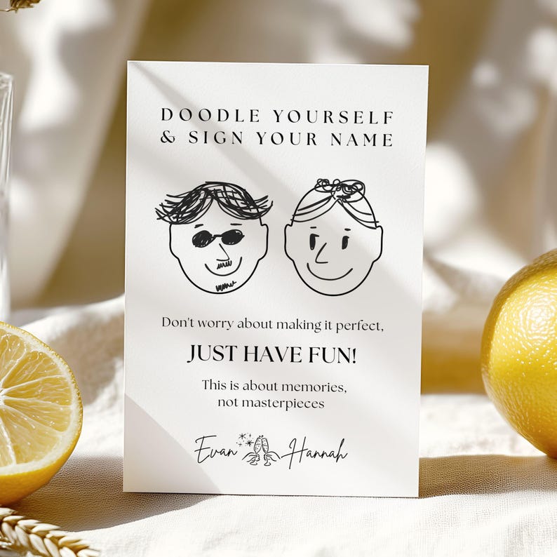 May include: A white card with black text and doodle illustrations. The text reads "DOODLE YOURSELF & SIGN YOUR NAME" and "JUST HAVE FUN!". Below the text are two doodle faces and the names "Evan" and "Hannah".