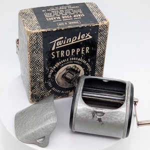 May include: A vintage Twinplex Stropper for double edge razor blades. The set includes a metal stropping device, a protective cover, and the original box. The box is black and tan with the Twinplex logo and product information.