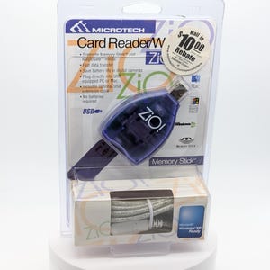 May include: A Microtech Card Reader W in a clear plastic package. The card reader is purple and has the text "ZiO!" printed on it. The package also includes a USB extension cable and supports Memory Stick and MagicGate media.