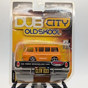 Può includere: Un modello pressofuso arancione di un furgone Ford Econoline '65, parte della serie Dub City Oldskool. Il modello è in una confezione di plastica trasparente con il testo "FRESH RIDE!" e "CLTR 033".
