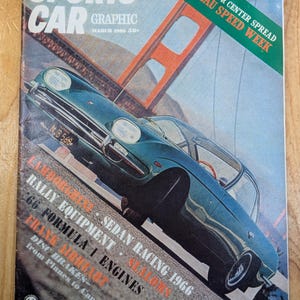 Puede incluir: Una portada de revista vintage "Sports Car Graphic" de marzo de 1960. La portada presenta un coche deportivo verde azulado en una carretera con el puente Golden Gate de fondo. El texto incluye "Nassau Speed Week" y temas relacionados con coches.