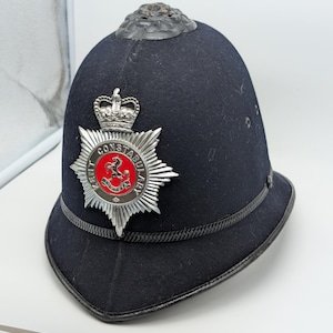 May include: A white ceramic mug with a black handle and the text "But First, Coffee" in a black, handwritten-style font. The mug is on a white surface.