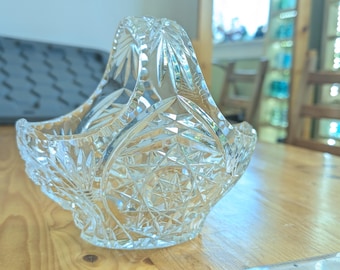 May include: A clear glass bowl with a cut glass design. The bowl has a handle and is shaped like a basket.