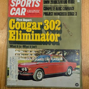 Puede incluir: Una portada de revista Sports Car Graphic de febrero de 1970. Presenta un coche rojo Cougar 302 Eliminator y el texto «TOYOTA/DATSUN FACE THE RACE ISSUE». El texto adicional incluye «BMW 2800CS/VOLVO 1800E» y «COMPLETE ARRC COVERAGE».