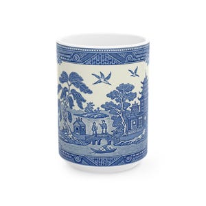 May include: A white ceramic mug featuring a blue and white design of a Chinese landscape with a pagoda, bridge, and two figures. The design is reminiscent of traditional blue and white china.