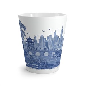 May include: A white ceramic mug with a blue and white design of a cityscape with a bridge and a pagoda. The design is reminiscent of traditional Chinese blue and white porcelain.