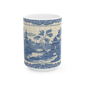 Peut inclure: Une tasse en céramique blanche avec un motif bleu et blanc représentant un paysage chinois avec un pont, une pagode et un bateau. Le motif rappelle la porcelaine bleue et blanche traditionnelle.