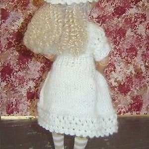 May include: A white crocheted dress with a white crocheted hat and striped stockings. The dress has a scalloped hem and the hat has a delicate lace pattern.