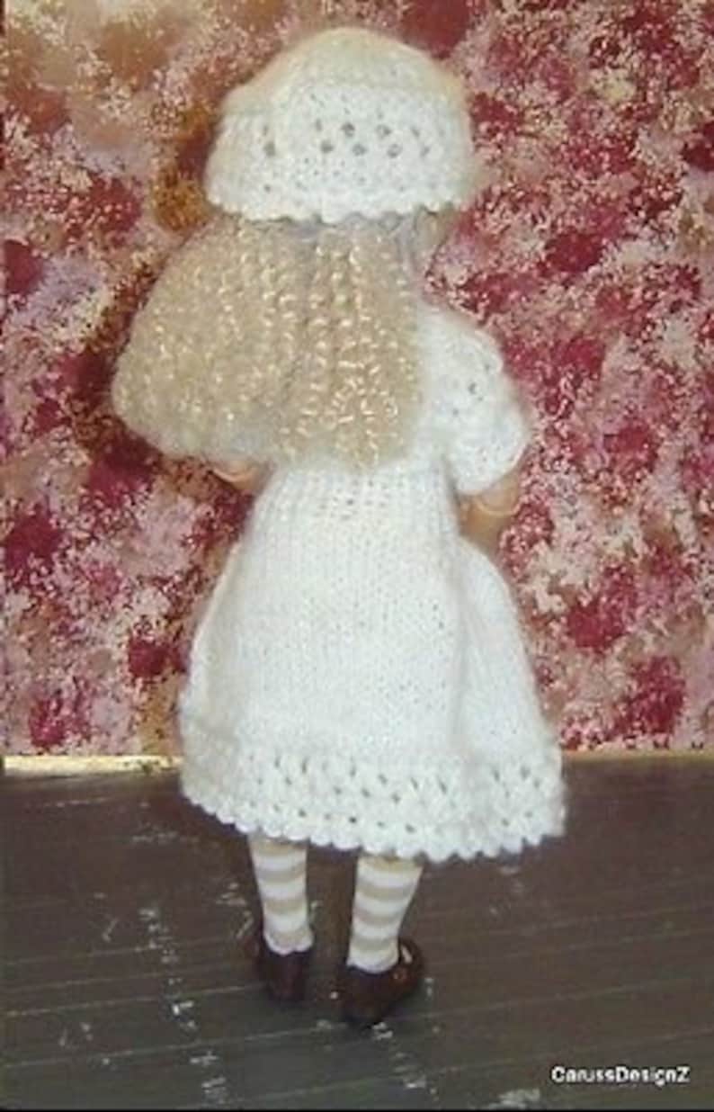 May include: A white crocheted dress with a white crocheted hat and striped stockings. The dress has a scalloped hem and the hat has a delicate lace pattern.