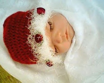 May include: A sleeping baby wearing a red crocheted hat with white fur trim and red flower embellishments.