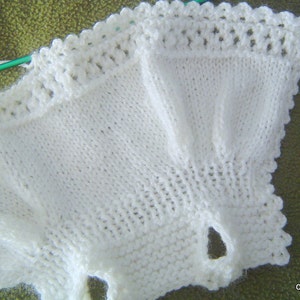 May include: White crocheted baby garment with a scalloped edge.