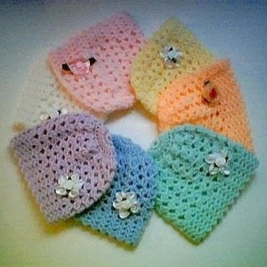 May include: A set of six crocheted baby hats in pastel colors, including pink, yellow, orange, light green, light blue, and lavender. Each hat has a crocheted flower embellishment.