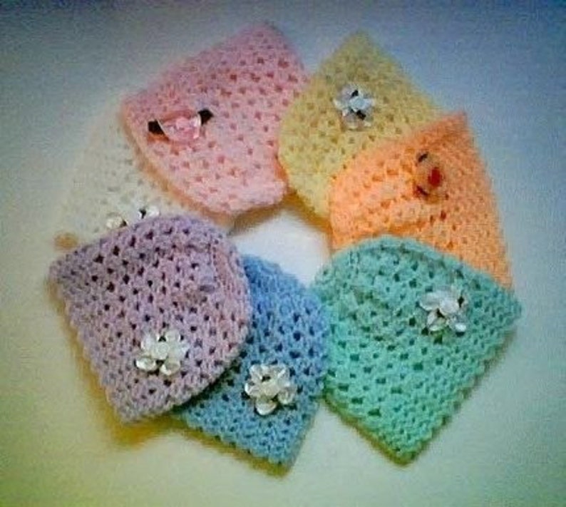 May include: A set of six crocheted baby hats in pastel colors, including pink, yellow, orange, light green, light blue, and lavender. Each hat has a crocheted flower embellishment.