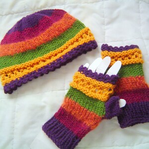 May include: A knitted hat and fingerless gloves set. The hat and gloves feature horizontal stripes in shades of purple, pink, orange, green, and yellow. The edges of the hat and gloves have a decorative, scalloped trim.