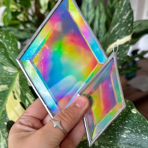 May include: Two diamond-shaped stained glass suncatchers with iridescent, multi-coloured surfaces that shift between blue, yellow, and pink hues. Each piece is framed in thin, silver-toned metal solder and features a small metal loop at the top.