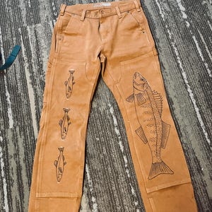 May include: Brown work pants with a fish design on the right leg and three smaller fish designs on the left leg.