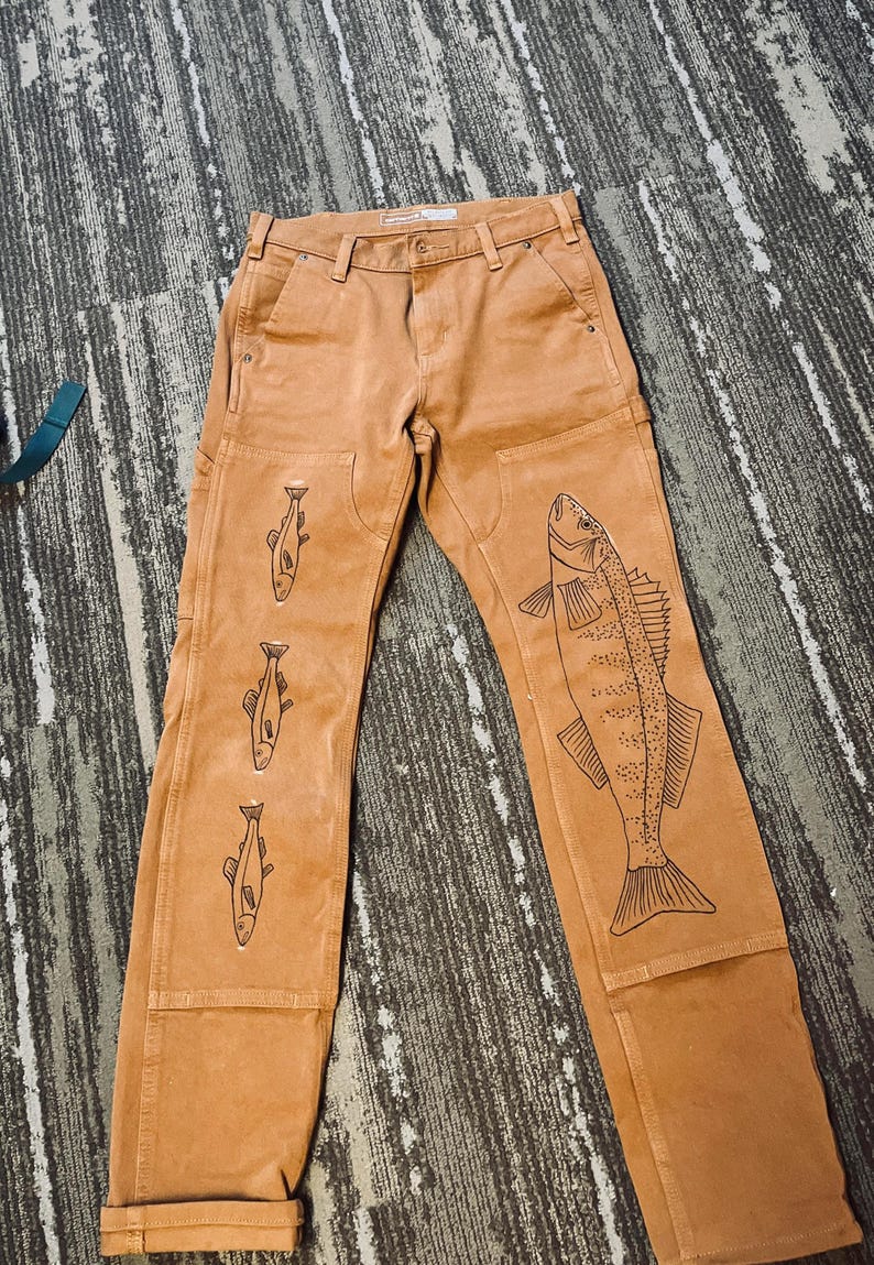 May include: Brown work pants with a fish design on the right leg and three smaller fish designs on the left leg.