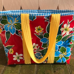 Puede incluir: Bolso tote rojo con estampado floral de flores azules, blancas y amarillas. Tiene asas amarillas y forro de cuadros vichy azul y blanco. El bolso est&aacute; hecho de un material duradero y es adecuado para transportar varios art&iacute;culos.