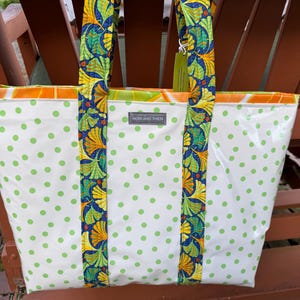 May include: White tote bag with green polka dots and straps featuring a colorful ginkgo leaf pattern. The bag has a rectangular shape and the text "NOW AND THEN" is visible on the front.