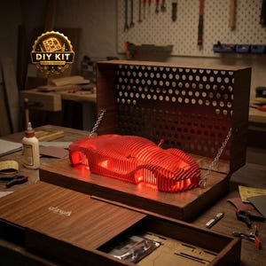 May include: A DIY kit featuring a red, layered, skeletal sports car model illuminated from within, housed in a dark wood display case with a perforated back panel and metal chains. The case lid features the text "alaxa" and a "DIY KIT" emblem.