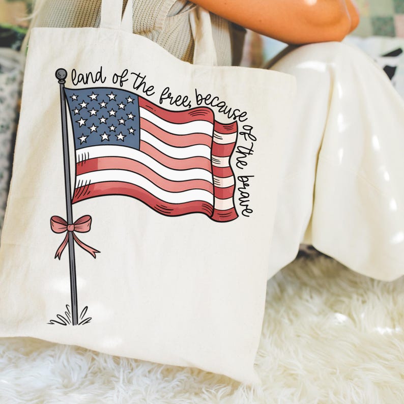 以下が含まれることがあります： 赤白青のアメリカ国旗と「land of the free, because of the brave」という文字が書かれた白いキャンバス地のトートバッグです。